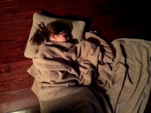 young girl sleeping on pillow and blanket