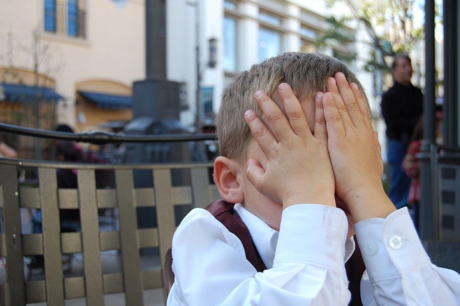 self-conscious emotions shame on little boy covering his face with his hands
