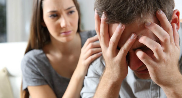 a woman consoles a man who appears distraught in his addiction relapse
