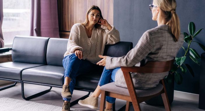 a woman sits on a couch listening to her therapist talk about outpatient detox