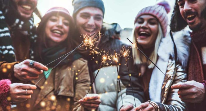 a group of young adults holding sparklers while outside participating in one of the many rewarding family activities for new years
