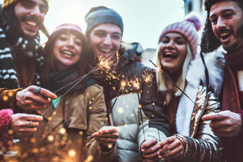 a group of young adults holding sparklers while outside participating in one of the many rewarding family activities for new years