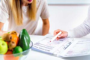 a person sits down with a nutritionist and reads and goes over nutrition education paperwork and lessons