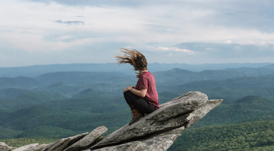 woman sitting on a cliff to represent high risk recovery situations