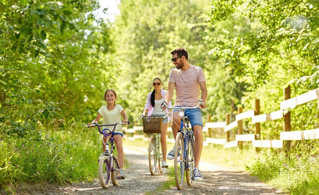 a family of three goes on a bike ride on trail in the forest enjoying one of many family therapy activities