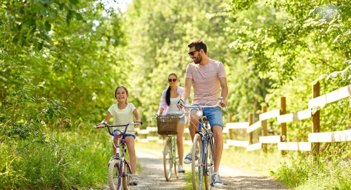 a family of three goes on a bike ride on trail in the forest enjoying one of many family therapy activities