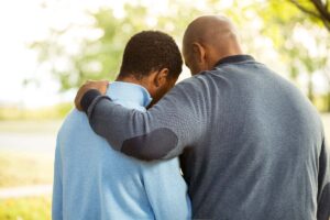an adult son is hugged by his father after discussing the effects of an alcoholic parents on children