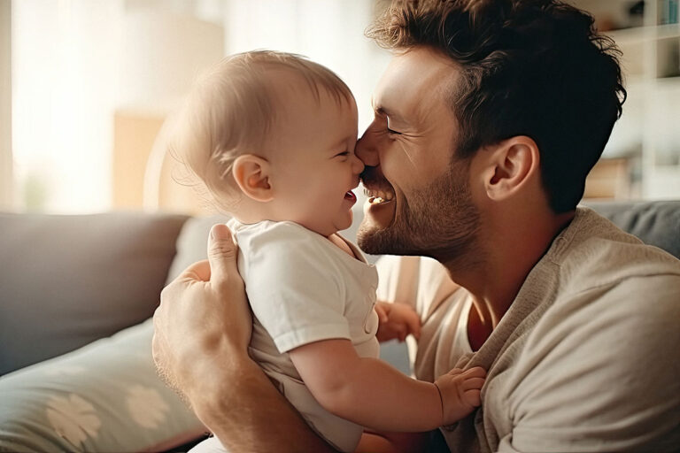 a man sits and holds his baby close to his face while smiling and thinking about the symptoms of meth exposure in infants