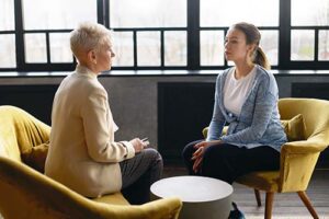 a therapist sits with a patient and discusses with the patient the benefits of an opiate addiction rehab