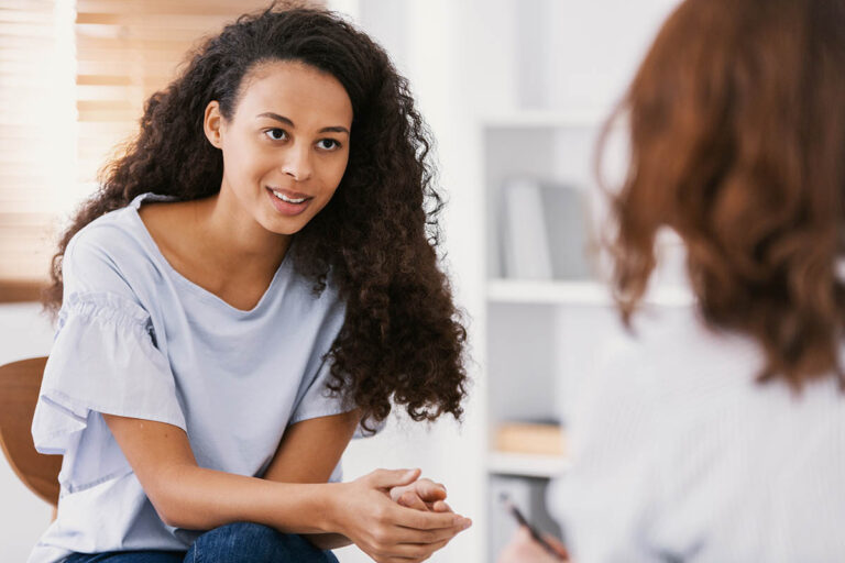 a woman looks and listens intently to the medical professional sitting across from her who is explaining the signs of compulsive eating disorder