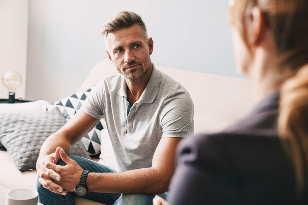 a man sits on the couch asking his therapist is body dysmorphia an eating disorder