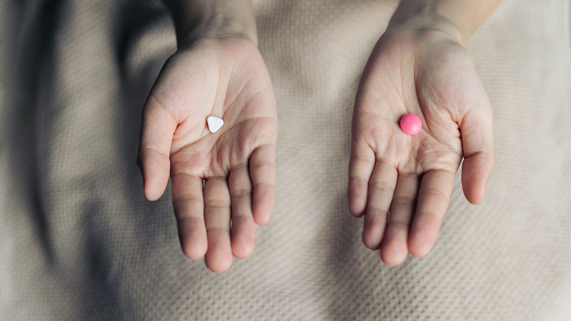 a person in detox rehab holds two different medicine pills in each hand