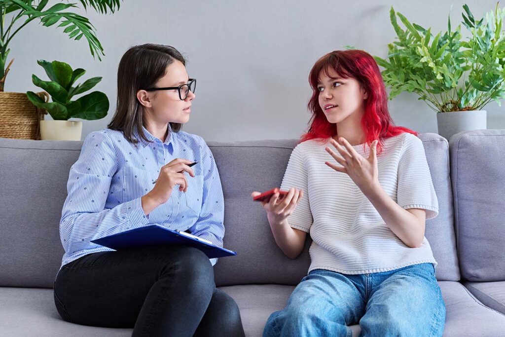 a therapist sits on a couch with a young person discussing the benefits of outpatient detox for withdrawal symptoms