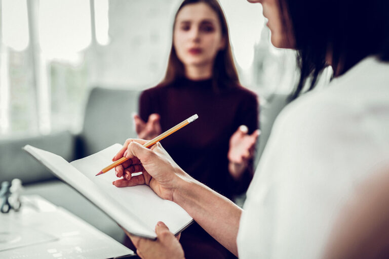 a woman sits with a professional who is writing down benefits of outpatient treatment for eating disorders for the woman